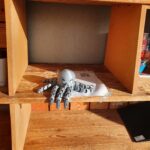 A gray 3d-printed octopus sitting inside a wooden shelf.